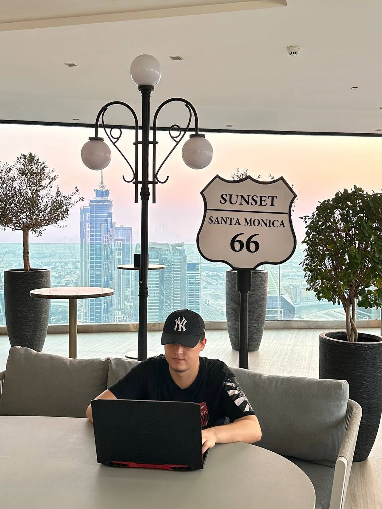 Said at a laptop on a grey sofa, a Route 66 sign behind him