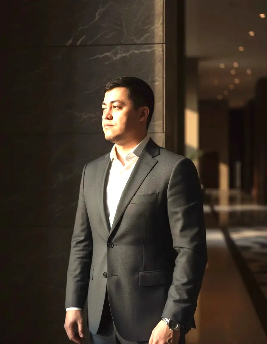 A man in a charcoal suit in a dim corridor